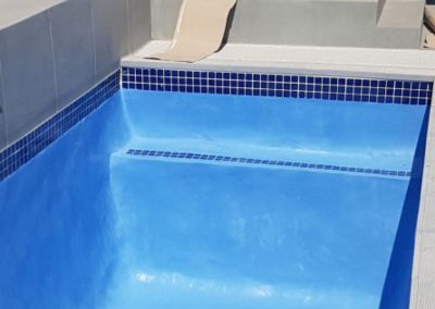 Empty finished small swimming pool of concrete, with blue interior, blue tiles.