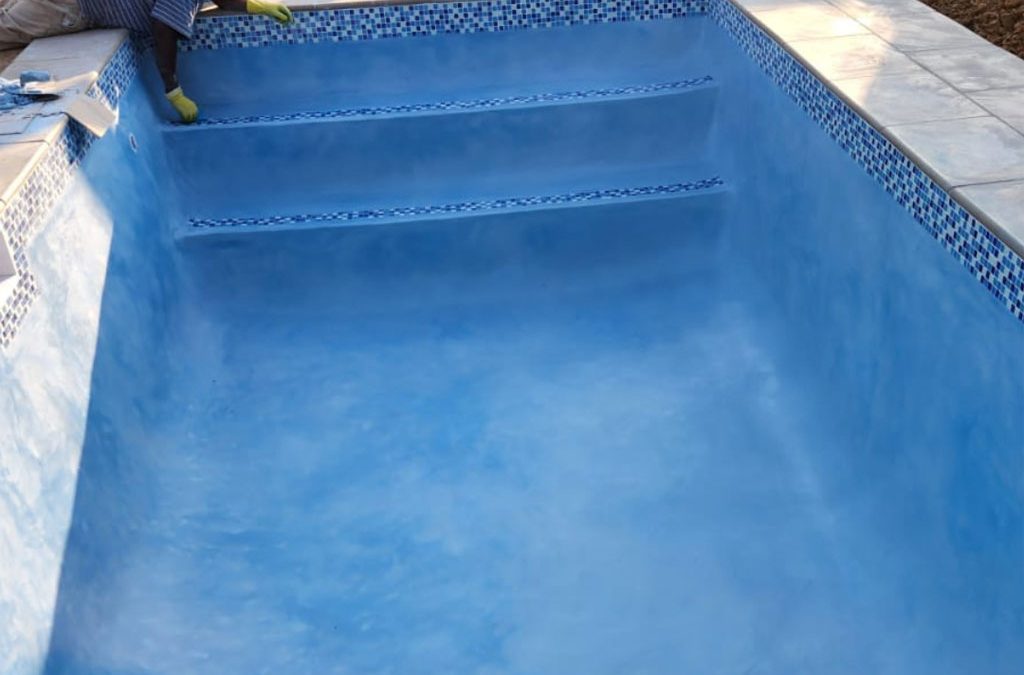 Small concrete pool project almost finished with blue interior.