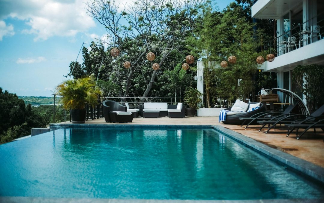woman in black shirt sitting on white chair near swimming pool during daytime