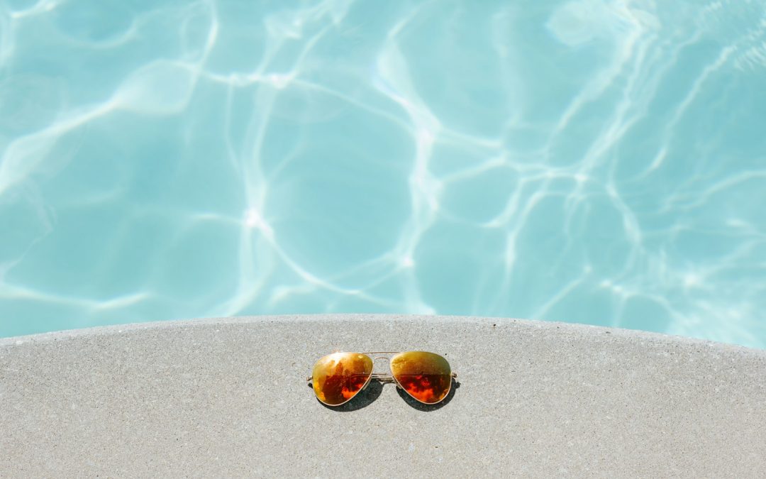 gold framed orange lens Aviator-style sunglasses beside pool